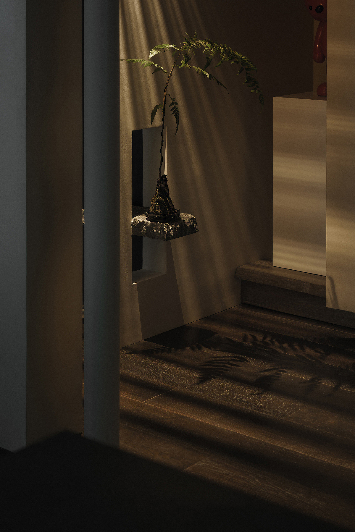 玄关顶部以细竹排列为吊顶,刻意制造出体量感仿佛穿插搭接在客厅的墙面之上,加强了两个区域的关联,而也与清透的材质之间形成了微妙的平衡,灯光从顶上打下,在玄关处留下暧昧的明暗阴影。