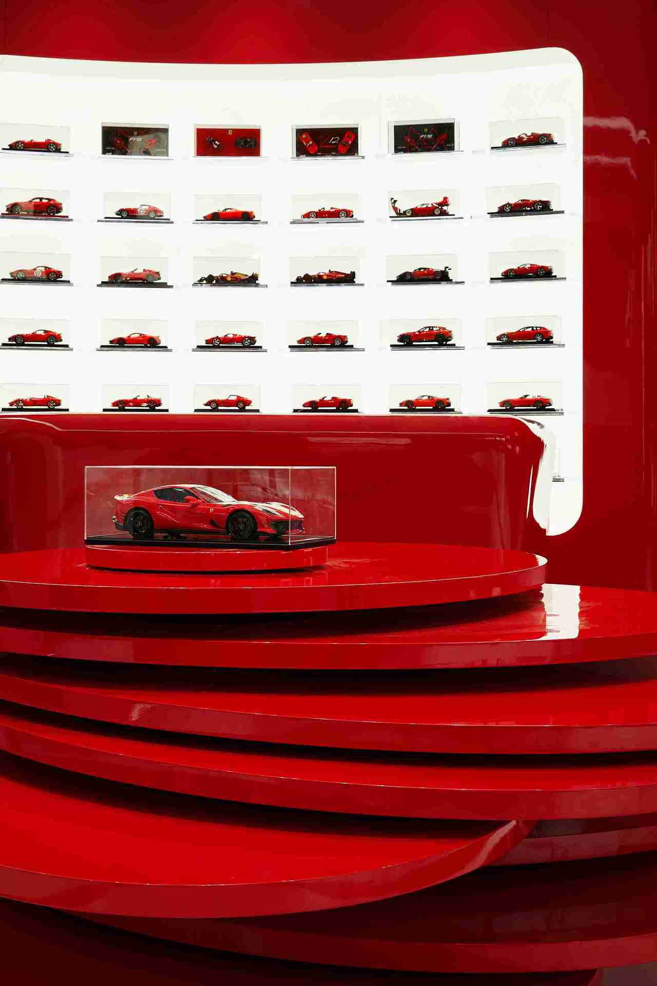 以意大利蒙扎(MONZA)赛道作为造型元素的接待台,整体柜体以法拉利展厅常用的带倒角柔和体块为造型基础,台面背后则是一面精心设计的车模墙,以阵列形式展示,既彰显了品牌特色,又增强了空间的艺术感。
<br>为确保立面的连贯性和整体美感,内部特别配置了发光灯板,营造出无缝衔接的立面效果。楼梯造型灵感源自阿根廷布宜诺斯艾利斯(BUENOS AIRES)赛道的经典元素,白色的外立面结合红色的内部通道营造出一种空间的张力。拾阶而上,顶部的黑白格设计融入法拉利的俱乐部文化元素,犹如从休息厅步入赛道的独特体验,为每一步征程增添庄重与仪式感。