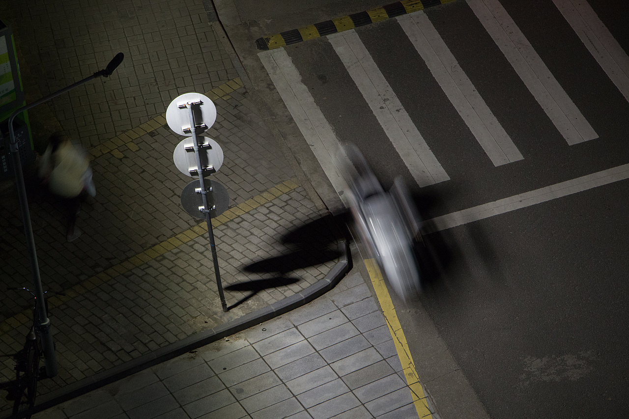 图二,拍摄于教学主楼的马路的转弯处,夜幕降临,天空变黑,路旁灯光刚亮,行人和车行于路上。