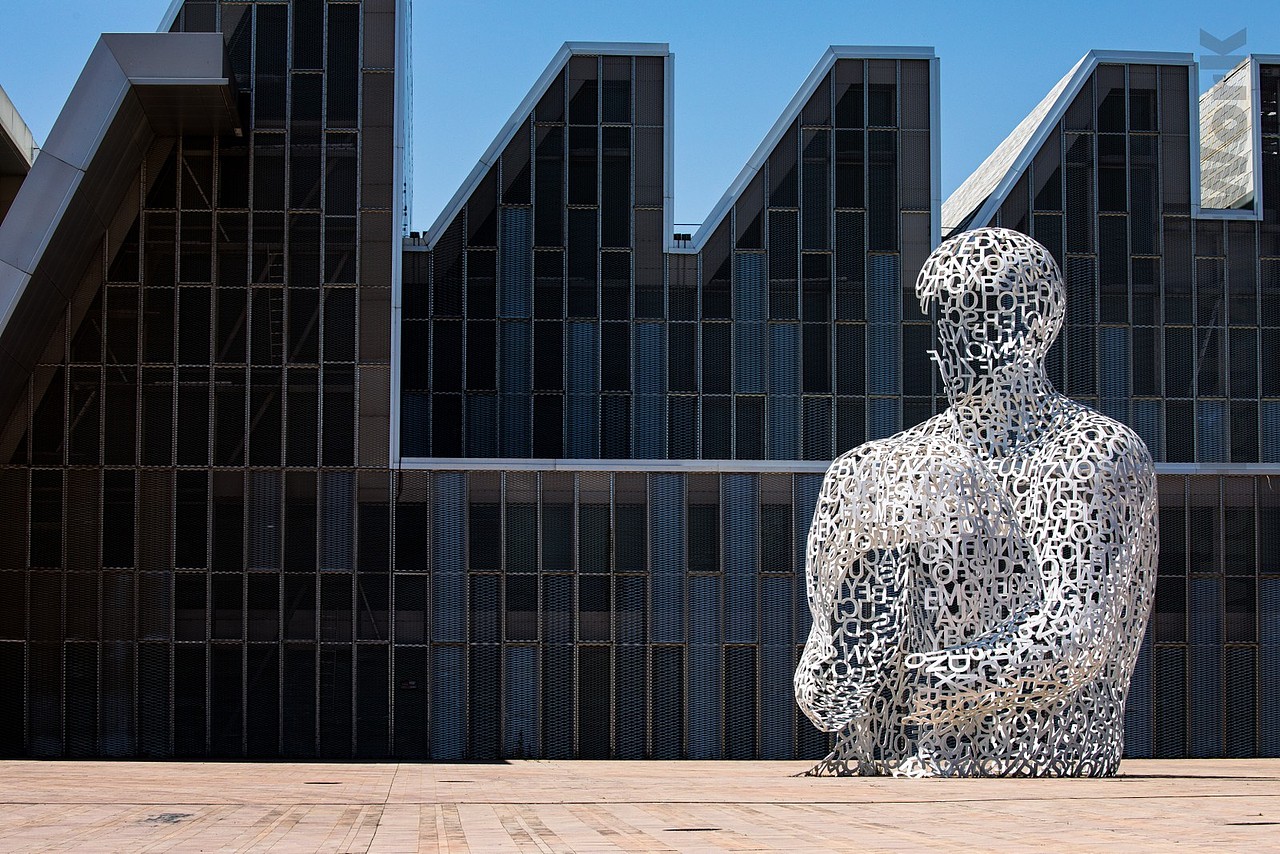 萨格拉萨会议中心的主楼蜿蜒曲折的屋顶,或许也来源于世博会的主题。这座建筑是由西班牙建筑师弗恩桑塔-尼托(Fuensanta Nieto)设计建造,整个场馆的屋顶由多层次的折现如水波般行程,远远的就吸引了我的注意力。这里现在作为音乐剧和戏剧的场地使用。在它前面伫立着的,是被仿无数的知名雕塑“埃布罗之魂”巨大而无脸的人物抱膝而坐,显出了脆弱与无助的姿态。雕塑家雅梅-普伦萨(Jaume Plensa) 意图让人清晰的反省自我,尊重自我价值,而遍布身体的字符则代表了我们被定义的外壳。嘛,这是我的理解……现代艺术嘛,其实并没有明确的定义可言,千人千面,每个人对其的理解都可以视为正确的,所以无需过度揣测,从自我的角度描述即可hhh~