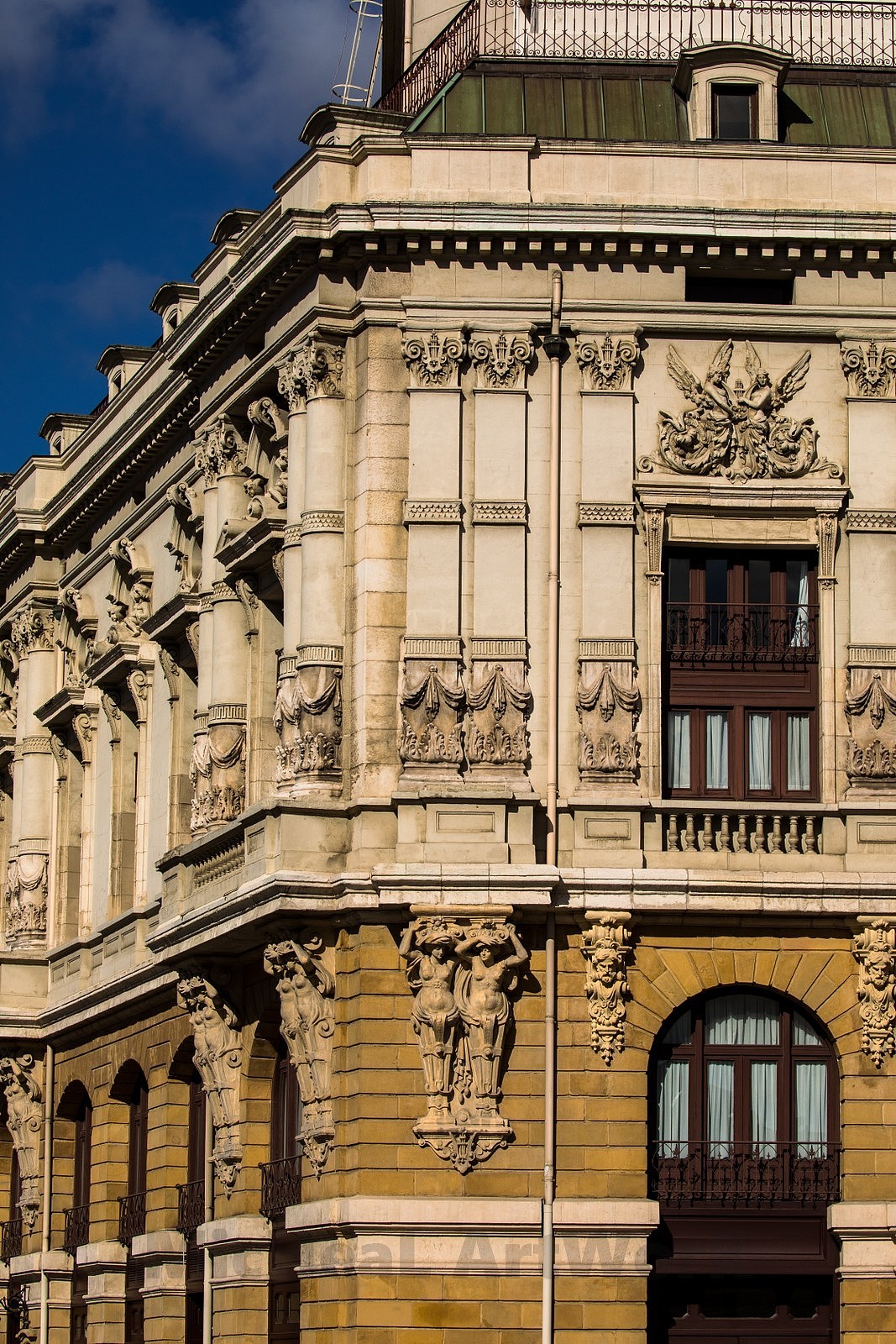 阿里亚加剧院(Arriaga Antzokia)就坐落在河对岸,而这一片区域开始就是毕尔巴鄂的老城区部分了,歌剧院由建筑师华金-鲁克瓦(Joaquín Rucoba)设计建造于1890年,运用了新巴洛克风格的它看着多少有点复古调调,檐部下布满了的雕塑女神柱搭配上层浮雕帷幕将戏剧气氛拉满。不过1983年8月,原建筑被严重的洪水破坏严重,之后得到重建。剧院的名字来源于胡安-克里斯托莫-德-阿里亚加(Juan Crisostomo de Arriaga)这位音乐家被称作“西班牙莫扎特”原因一方面是他德神童身份,其次他们有着同一天的生日,阿里亚加出生于1806年1月27日,这天是莫扎特50岁生日。父亲同样是音乐家出身,同样有点鸡娃= =1823年,他已然能写出震惊音乐学院院长的曲调,这时他仅仅17岁。然后就是另一方面的相同,这位天才在1826年1月17日病逝……20岁差10天……肺结核+疲惫彻底摧毁了这位天才,莫扎特还至少活到35……留下不少杰作,这位很多作品因在校期间创作甚至都没流传下来……= =哎……艺术家…活着才最关键啊!