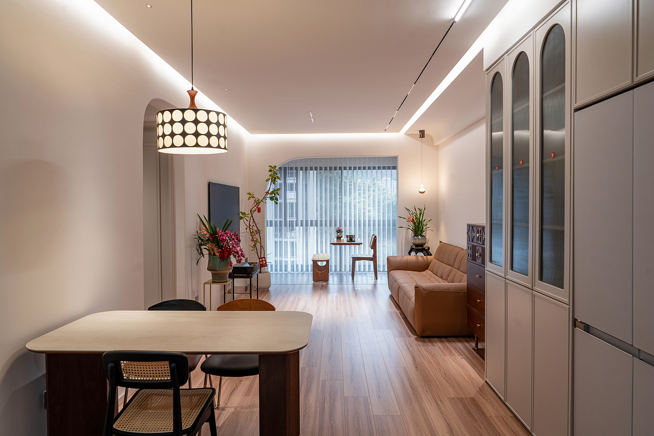 “客厅与餐厅一体化设计,开放式布局让空间通透明亮。现代吊灯散发柔和的光线,搭配木质地板与咖色沙发,营造温馨的居家氛围。”